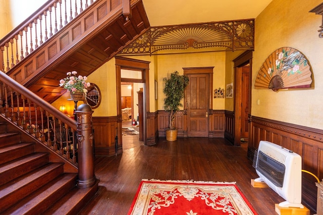 foyer entrance with wooden walls, a towering ceiling, dark hardwood / wood-style floors, and heating unit