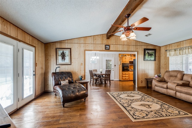 living room featuring wooden walls, hardwood / wood-style floors, vaulted ceiling with beams, ceiling fan, and a textured ceiling