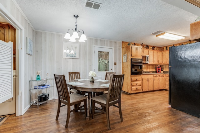 dining area featuring crown molding, a textured ceiling, wood-type flooring, and a chandelier