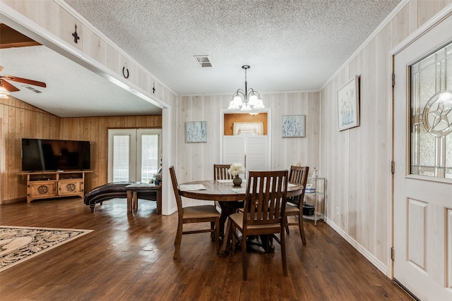 dining area featuring ceiling fan with notable chandelier, dark wood-type flooring, crown molding, and a textured ceiling