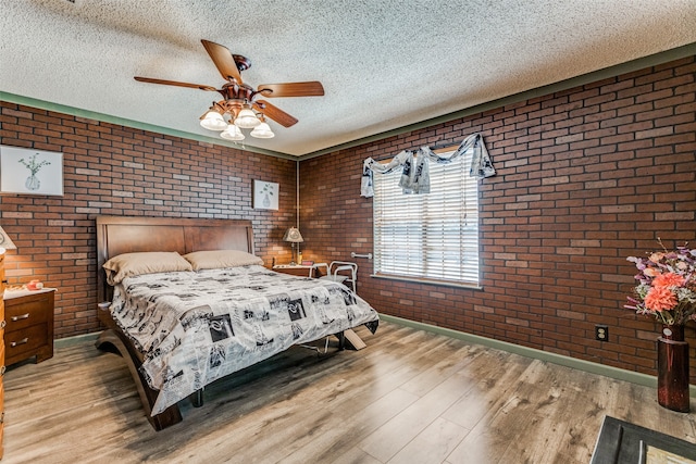 bedroom featuring hardwood / wood-style floors, ceiling fan, brick wall, and a textured ceiling