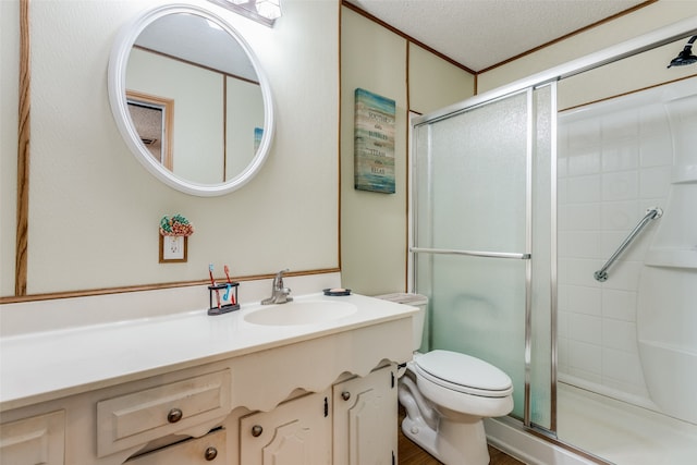 bathroom with vanity, toilet, a textured ceiling, and a shower with door