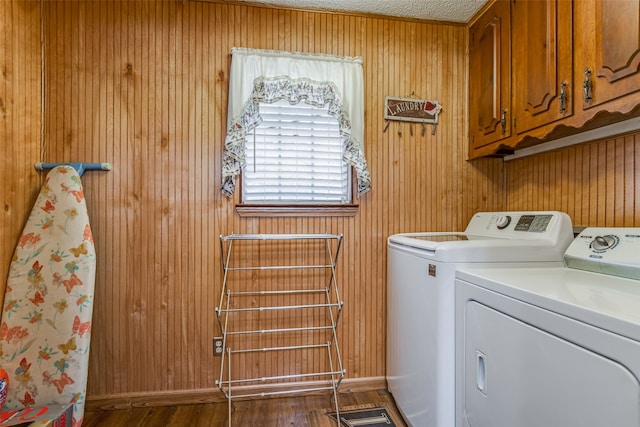 laundry area featuring cabinets, wood walls, and separate washer and dryer