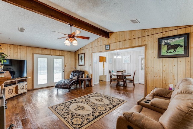 living room with a textured ceiling, dark wood-type flooring, wood walls, ceiling fan, and vaulted ceiling with beams