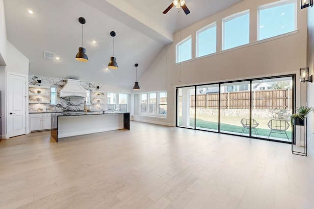 unfurnished living room featuring ceiling fan, high vaulted ceiling, and light wood-type flooring