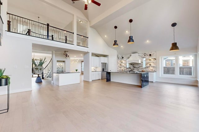 living room with sink, ceiling fan, high vaulted ceiling, and light hardwood / wood-style flooring