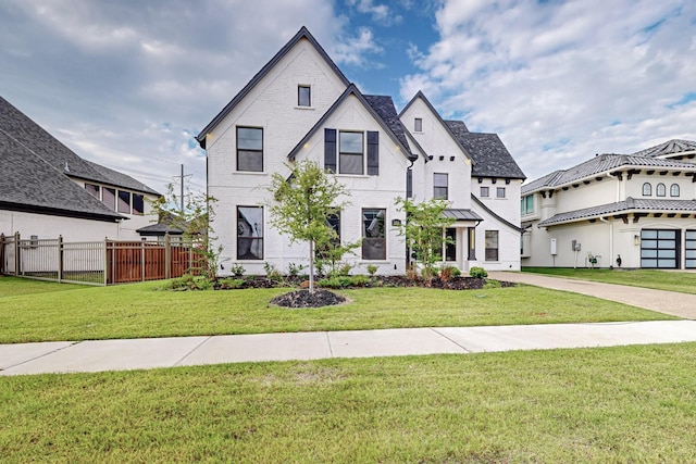 view of front of property with a front lawn, fence, and brick siding