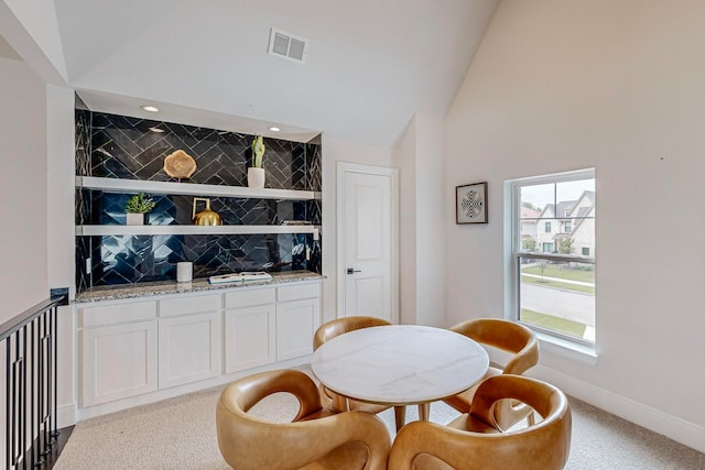 carpeted dining room with vaulted ceiling