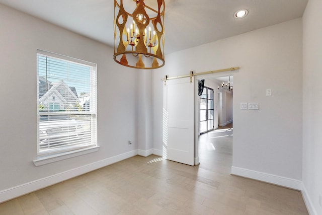 spare room with a barn door and a notable chandelier