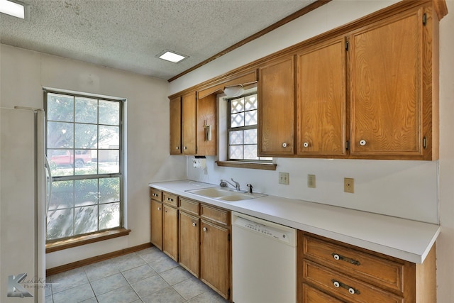 kitchen with a wealth of natural light, white appliances, sink, and a textured ceiling