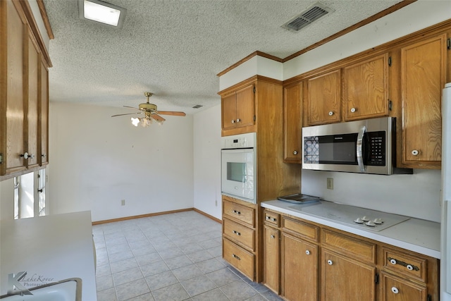 kitchen with ceiling fan, a textured ceiling, light tile patterned floors, and white appliances