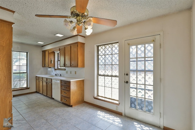 kitchen with plenty of natural light, light tile patterned floors, and white dishwasher