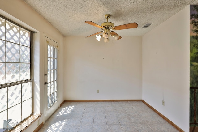 tiled spare room with ceiling fan and a textured ceiling