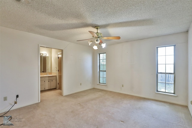 unfurnished room with ceiling fan, light colored carpet, a textured ceiling, and a healthy amount of sunlight