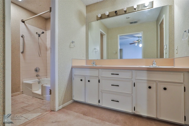 bathroom with ceiling fan, vanity, a textured ceiling, and shower / bathtub combination