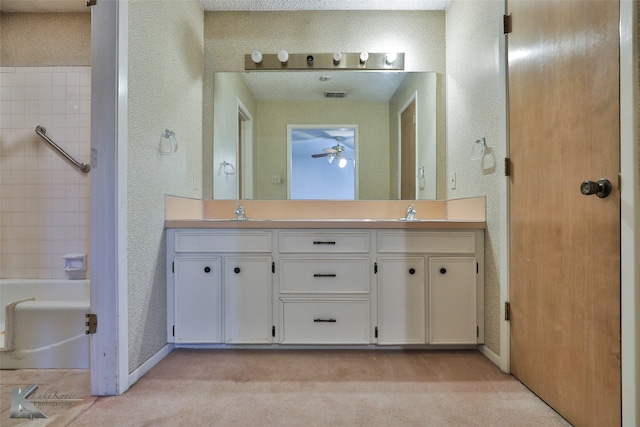 bathroom with ceiling fan, vanity, a textured ceiling, and a tub