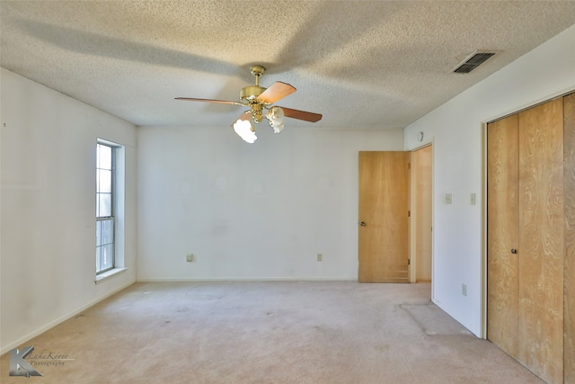 unfurnished room featuring a textured ceiling, ceiling fan, and light colored carpet