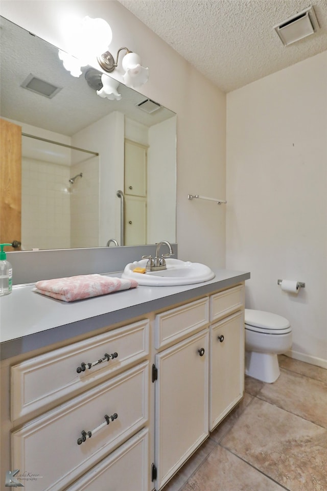 bathroom featuring walk in shower, vanity, tile patterned flooring, toilet, and a textured ceiling