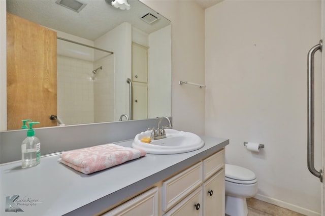 bathroom with vanity, a textured ceiling, a tile shower, tile patterned floors, and toilet