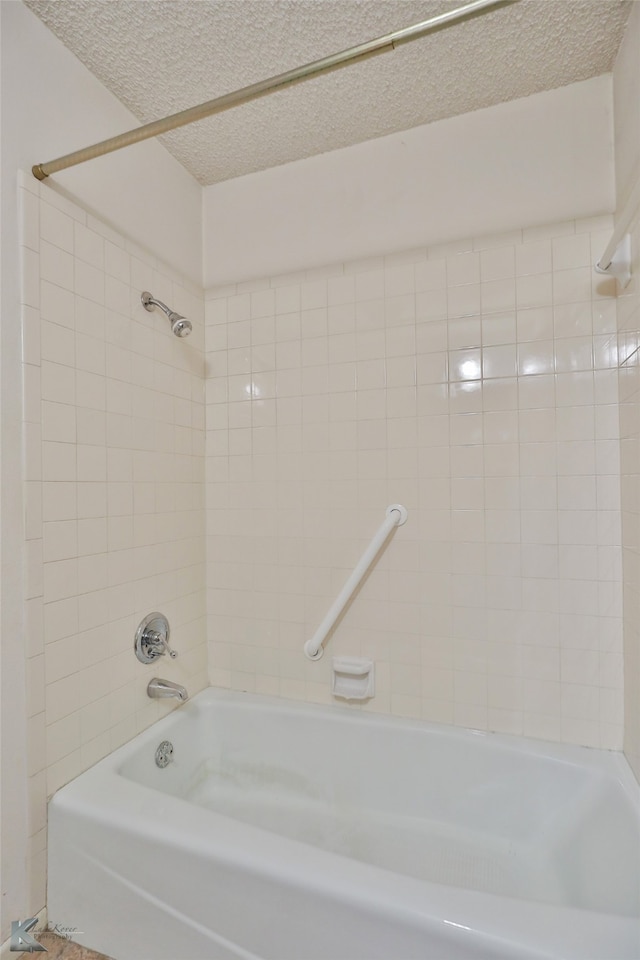 bathroom with tiled shower / bath and a textured ceiling