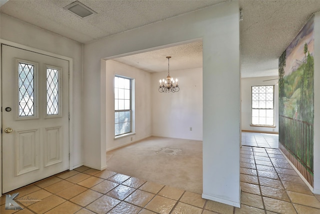 foyer with light carpet, an inviting chandelier, and a textured ceiling