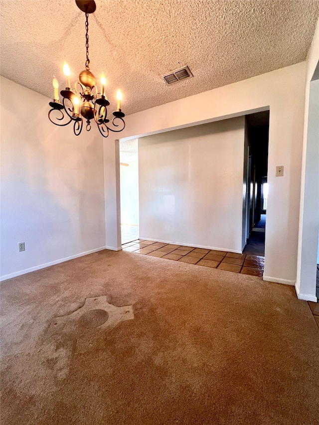 empty room featuring dark colored carpet, a notable chandelier, and a textured ceiling