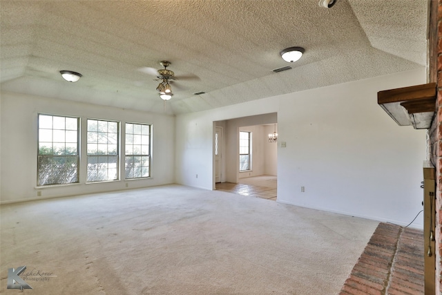 unfurnished living room with ceiling fan, plenty of natural light, a textured ceiling, and light colored carpet