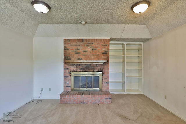 unfurnished living room with a brick fireplace, vaulted ceiling, a textured ceiling, and carpet flooring