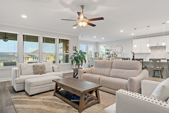 living room featuring light hardwood / wood-style flooring, ceiling fan, and ornamental molding