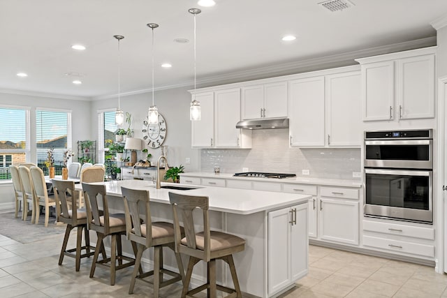 kitchen with pendant lighting, a center island with sink, white cabinetry, and appliances with stainless steel finishes