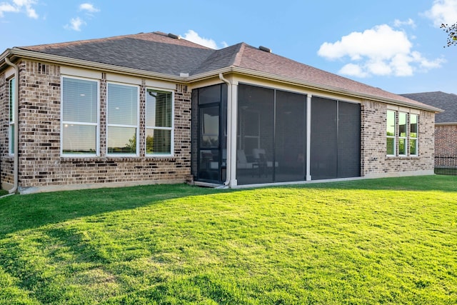 back of property featuring a lawn and a sunroom