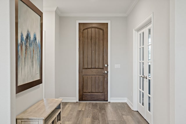 entryway with ornamental molding, french doors, and light hardwood / wood-style flooring