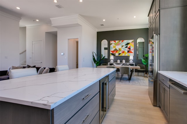 kitchen featuring light wood-type flooring, crown molding, stainless steel appliances, a center island, and light stone countertops