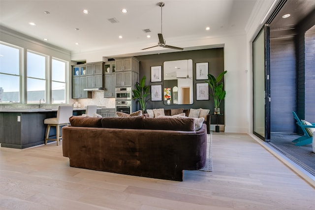 living room with light hardwood / wood-style flooring, ceiling fan, and ornamental molding