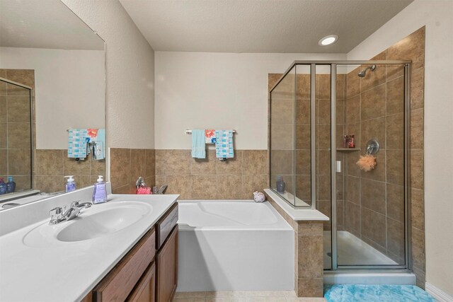 bathroom featuring vanity, a textured ceiling, plus walk in shower, and tile patterned flooring