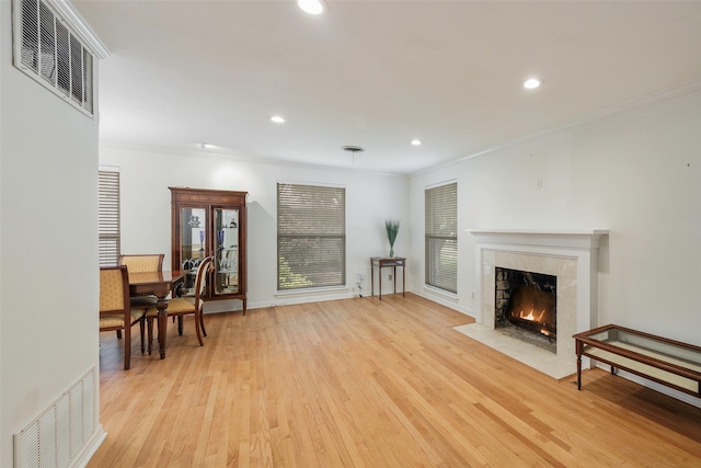 living room featuring a fireplace, light wood-type flooring, and crown molding