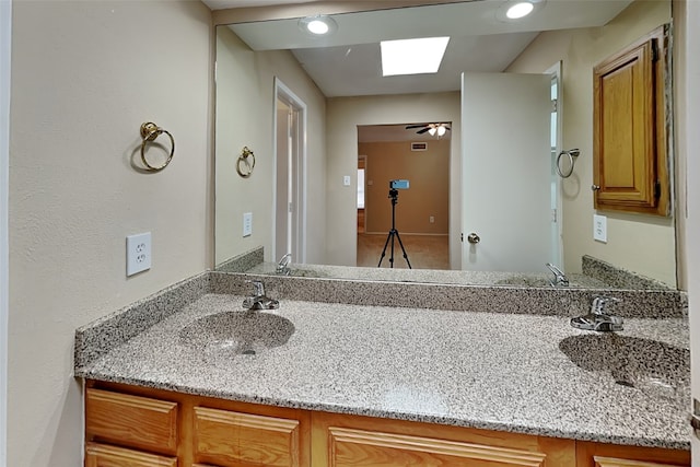 bathroom featuring vanity, ceiling fan, and a skylight