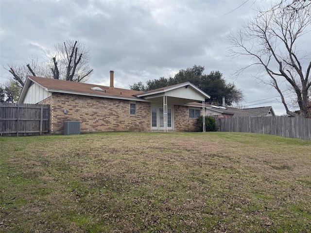 rear view of property featuring a yard and central AC unit