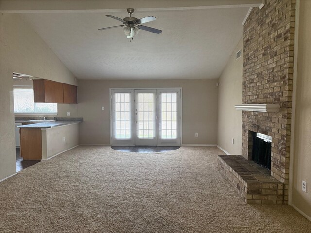 unfurnished living room with ceiling fan, lofted ceiling, a wealth of natural light, and a brick fireplace