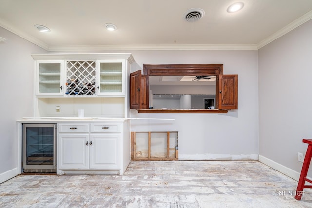 bar with white cabinetry, crown molding, ceiling fan, and beverage cooler