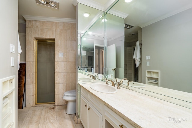 bathroom featuring toilet, vanity, a shower with shower door, tile walls, and ornamental molding