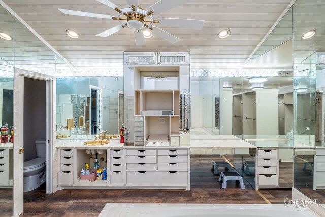 bathroom with hardwood / wood-style floors, vanity, vaulted ceiling, ceiling fan, and toilet