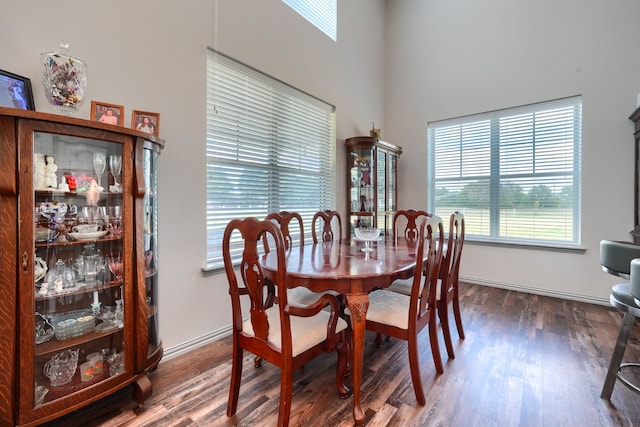 dining room with dark wood-type flooring and a towering ceiling