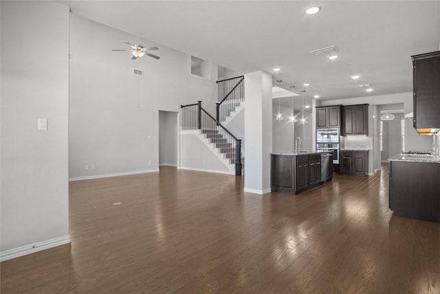 unfurnished living room with sink, dark wood-type flooring, and ceiling fan