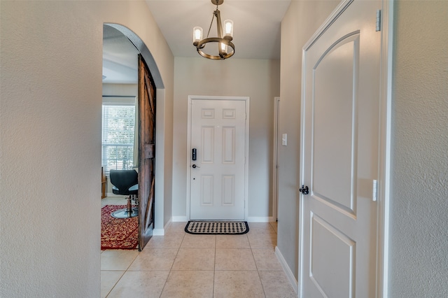 tiled entryway with a notable chandelier