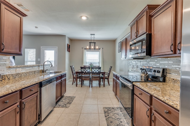 kitchen featuring hanging light fixtures, stainless steel appliances, sink, and decorative backsplash