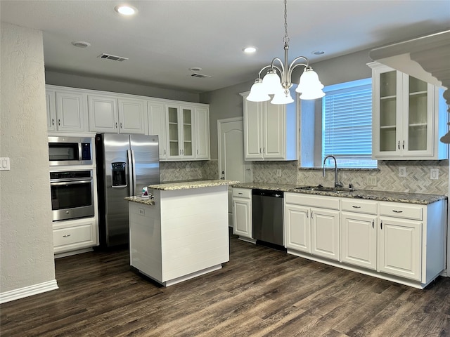 kitchen with appliances with stainless steel finishes, white cabinetry, dark hardwood / wood-style floors, pendant lighting, and sink