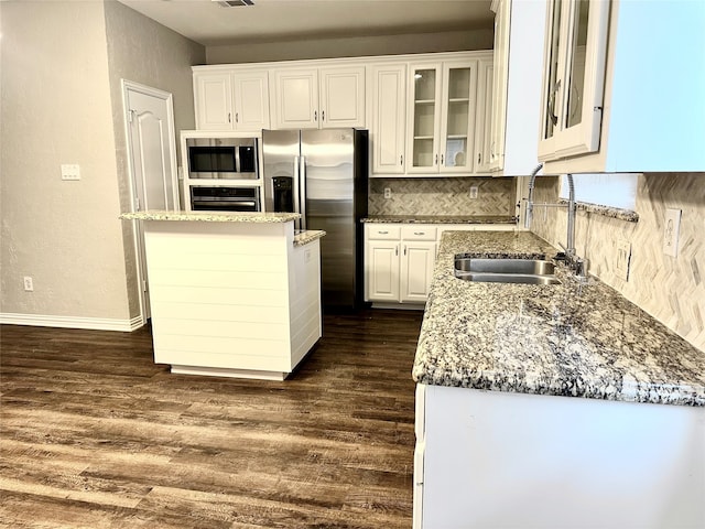 kitchen featuring stainless steel appliances, backsplash, sink, white cabinetry, and dark hardwood / wood-style flooring