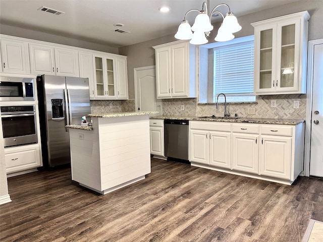 kitchen with dark hardwood / wood-style floors, stainless steel appliances, sink, pendant lighting, and white cabinets