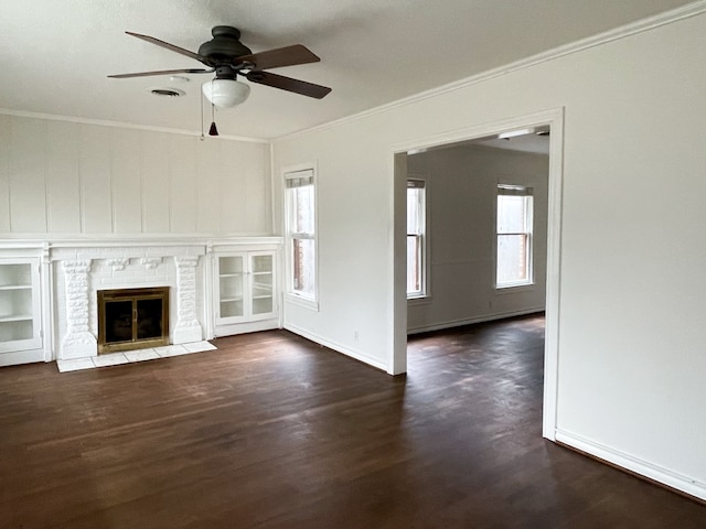 unfurnished living room featuring ornamental molding, ceiling fan, a fireplace, and dark hardwood / wood-style flooring